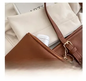 Detail of a brown Saffiano leather tote bag featuring a mini pouch for wireless earbuds
