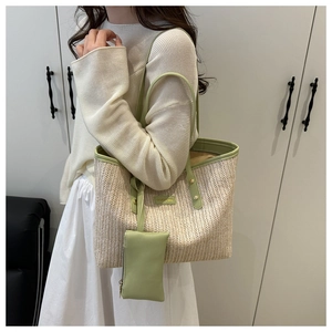 Detail of hand-woven straw tote bag with green trim and matching zipper pouch accessory
