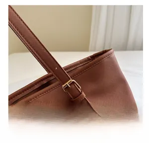Close-up of adjustable brown leather shoulder strap with a gold metal buckle on tote bag