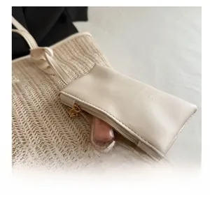 Detail of the woven straw tote bag featuring a small detachable leather coin purse hanging