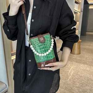 Green stone pattern bucket bag with pearl handle and crossbody strap on black shirt