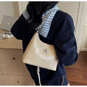 Détail du sac beige en cuir verni plissé avec breloque étoile argentée et chaîne