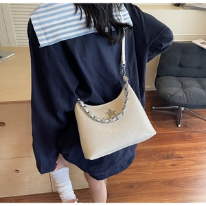 Détail du sac bandoulière crème en similicuir avec étoile argentée porté par le mannequin