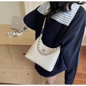 Gros plan d'un sac demi-lune blanc avec chaîne argentée et pendentif étoile