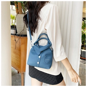 Detail of navy blue shirt-shaped handbag with leather texture and white buttons