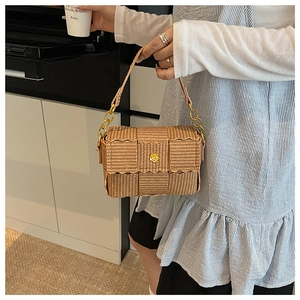 Detail of woven square bag featuring a gold flower lock and wavy flap design