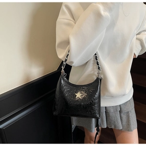 Détail du sac hobo noir brillant avec badge étoile argentée et chaîne en métal épais