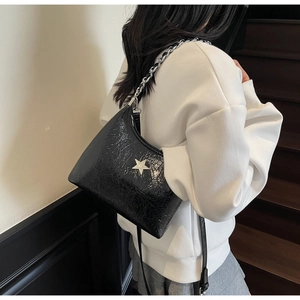 Détail du sac à bandoulière en cuir verni noir avec ornement d'étoile et chaîne