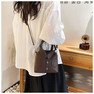Detail of a brown leather crossbody bag with a creative shirt-style collar and button design