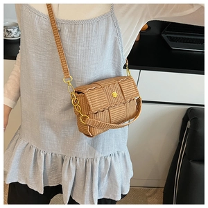 Close-up of woven crossbody bag featuring a golden flower clasp and wavy flap detail