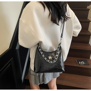 Détail du sac sous l'aisselle en cuir verni noir avec logo étoile argenté et grosse chaîne