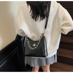 Détail du sac à bandoulière noir avec étoile dorée et chaîne argentée sur modèle