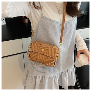 Detail of woven straw crossbody bag with gold rose buckle and adjustable metal chain strap