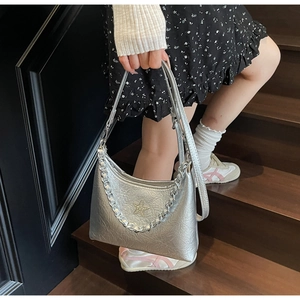 Détail du sac argenté métallisé avec bandoulière chaîne et emblème étoile sur modèle