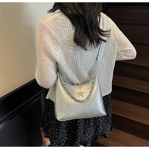 Sac argenté métallisé avec bandoulière chaîne et boucle étoile porté par un mannequin