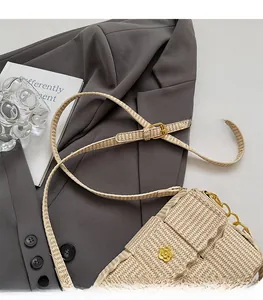 Detail of woven square crossbody bag with gold floral buckle and adjustable strap