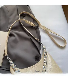 Détail du sac beige plissé avec chaîne argentée et breloques métalliques en forme d'étoile