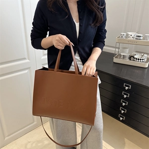 Brown textured leather tote bag with embossed lettering and detachable shoulder strap