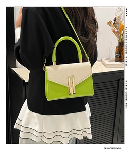 Detail of green and beige woven crossbody bag with gold metal lock on a female model