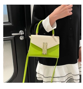 Close-up of woven fabric texture and green leather flap on a stylish crossbody bag