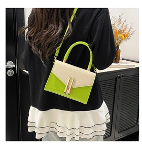 Detail of green leather and straw texture shoulder bag with gold metal lock closure