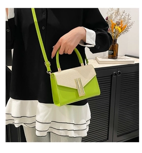 Detail of woven texture flap on lime green and beige leather crossbody bag with gold lock