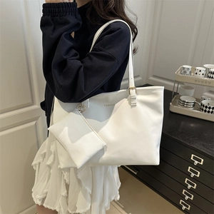 White minimalist PU leather tote bag set with golden hardware worn by a fashion model