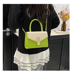 Detail of green leather and beige woven flap on a small crossbody bag with gold lock