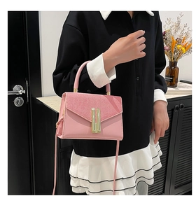 Pink crossbody bag with glossy texture and elegant gold bar buckle shown in a lifestyle setting