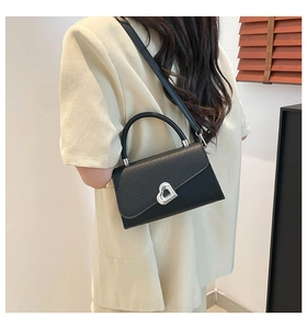 Borsa a tracolla nera con patta trama lucertola e fibbia a cuore argento indossata