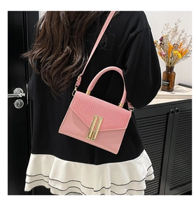 Detailed view of a pink crossbody bag with woven texture flap and golden lock