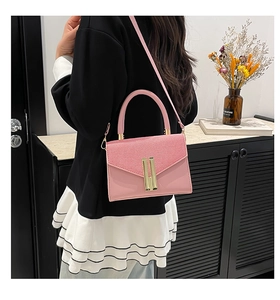 Pink crossbody bag with woven texture lid and gold metal buckle shown on a model