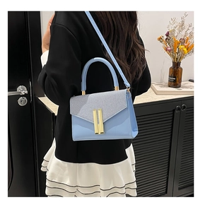 Vue détaillée du sac bandoulière bleu clair avec détails dorés porté par un mannequin