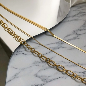 Three-piece layered gold necklace set featuring snake, rope, and oval link chains