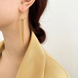 Boucles d'oreilles pendantes à longs pompons dorés 18K sur modèle au style chic
