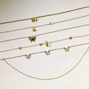 Détail de pendentifs papillon dorés avec colliers à chaînes fines multicouches