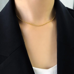 Gros plan d'un collier ras du cou doré à perles sur un mannequin en blazer noir