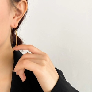 Orecchini lunghi a U in oro lucido indossati da una modella per un look moderno