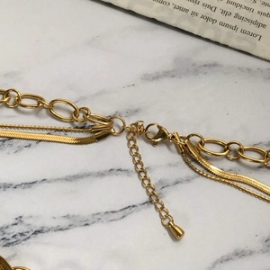 Detail of gold multi-layer necklace with snake, bead and oval chains and lobster clasp