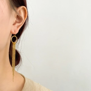 Détail de longues boucles d'oreilles à pompons plaquées or 18 carats sur un modèle