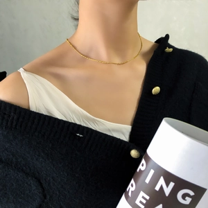 Détail d'un collier ras du cou doré à perles minimaliste porté sur la clavicule