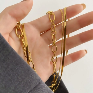 Close-up of triple-layered gold necklaces including chunky link and sleek snake chain