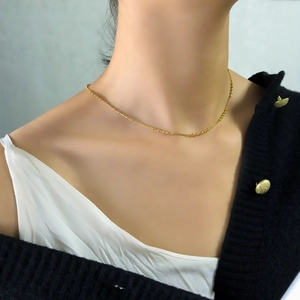 Détail d'un collier plaqué or avec de petites perles sur une chaîne minimaliste