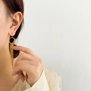 Détail de boucles d'oreilles longues à pompon plaquées or 18 carats portées par un modèle