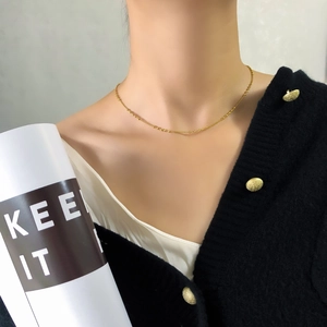 Détail d'un collier à billes minimaliste en or porté par un mannequin pour le style