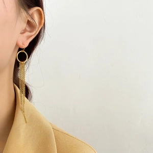 Détail de longues boucles d'oreilles dorées à pompons portées par un mannequin