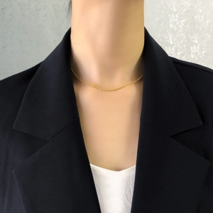 Gros plan d'un collier ras du cou doré minimaliste porté sur une tenue d'affaires chic