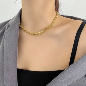 Close-up of layered gold Cuban link and snake chain necklace on model neck