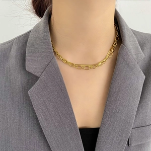 Detail of layered gold snake chain and oval link necklace on a grey blazer model