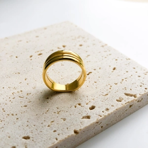 Dettaglio anello dorato minimalista a doppio strato su pietra travertino beige